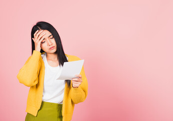 Portrait of beautiful Asian young woman sad tired strain holding paper calculating bills on hand, female person problem she hold worried over bill, studio shot isolated on pink background - obrazy, fototapety, plakaty