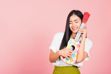 Portrait of happy Asian beautiful young woman teen confident smiling face hold acoustic Ukulele...