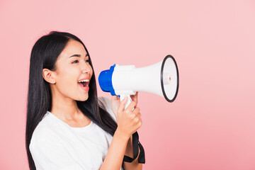 Portrait of happy Asian beautiful young woman teen confident smiling face holding making announcement message shouting screaming in megaphone, studio shot isolated on pink background, with copy space