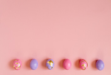 Violet and pink Easter eggs on the pink background, copy space.