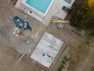 Drone shot of pool construction site with concrete pad for heat pump and pool house in garden in austria