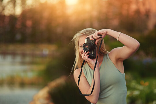 Leave no moment uncaptured. Portrait of a young woman taking photos on her camera outside.