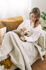 Young girl with happy soft cuddly white cat lying in lap enjoying and purring at home warm and cozy atmosphere