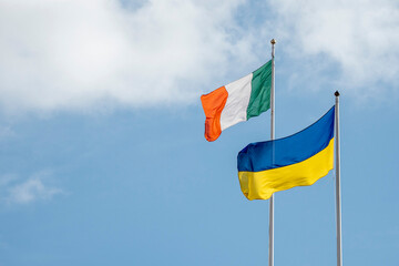 National flag Republic of Ireland and Ukraine against blue cloudy sky. Copy space