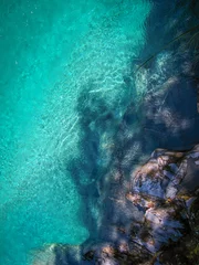 Foto op Plexiglas Koraalgroen Bovenaanzicht van een rots in de buurt van een helderblauwe oceaan