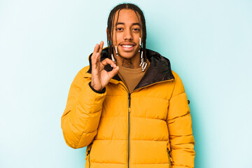 Young African American man isolated on blue background cheerful and confident showing ok gesture.