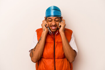 Young African American man isolated on white background covering ears with hands.