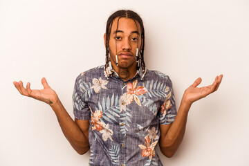 Young African American man isolated on white background doubting and shrugging shoulders in...