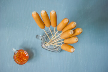 Cooked chicken sausage skewers on a plate with dipping sauce are placed on the table.