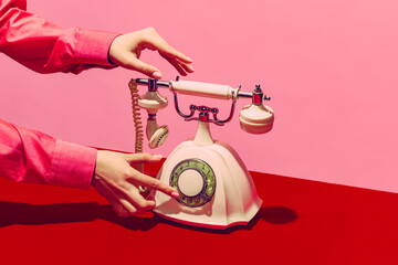Pop-art fotografie. Retro-objecten, gadgets. Vrouwelijke hand met handset van vintage telefoon geïsoleerd op roze en rode achtergrond. Vintage, retro mode-stijl