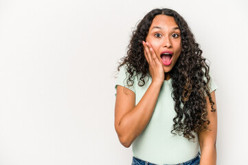 Young hispanic woman isolated on white background shouts loud, keeps eyes opened and hands tense.