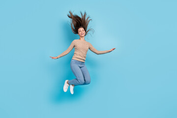 Photo of nice pretty cheerful lady jump have fun wind blow hairdo wear beige sweater isolated blue color background