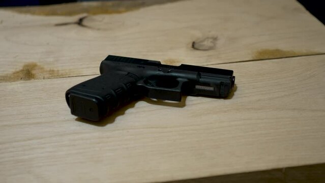 A handgun left on a wooden bench at a crime scene with police lights flashing - sliding view