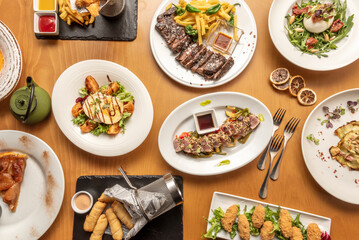 Set of varied international food dishes, with Venezuelan tequeños, Japanese red tuna tataki, Spanish barbecued entrecote, Italian burrata salad, Spanish croquettes with serrano ham
