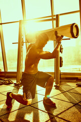 Portrait of a handsome man doing push ups exercise with modern weight equipment in rays of sunlight...