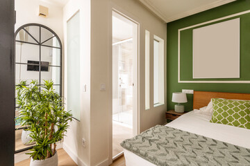 Room with king size bed and en-suite bathroom with glass partitions and decorative indoor plants