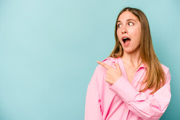 Young caucasian woman isolated on blue background points with thumb finger away, laughing and carefree.