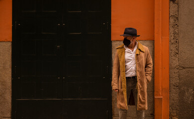 Obraz na płótnie Canvas Portrait of adult man in hat and mask against wall on street. Madrid, Spain