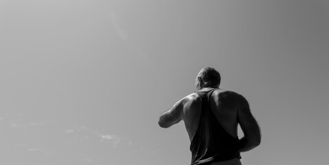 Plakat Monochrome of rear view of adult man on beach against sunny sky.