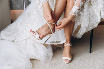 Wedding. Bride in white dress puts on shoes
