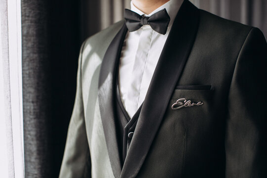 Wedding. Groom. A young man in a suit and a white shirt with a bow tie stands in a room near the window