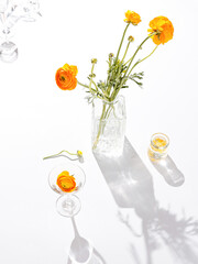 Vertical shot of cute orange flowers placed in a glass vase with lights reflecting off of it