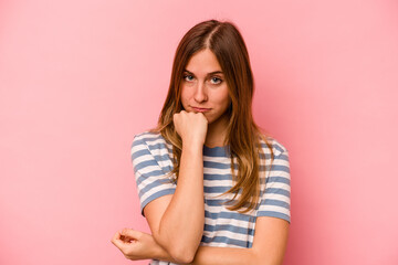 Young caucasian woman isolated on pink background suspicious, uncertain, examining you.