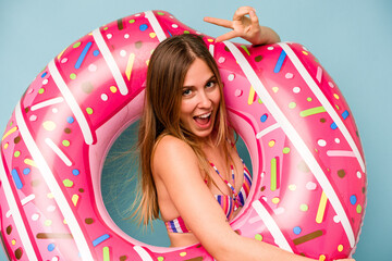 Young caucasian woman holding air mattress isolated on blue background