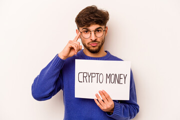 Young hispanic man holding a crypto money placard isolated on white background pointing temple with finger, thinking, focused on a task.