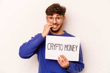 Young hispanic man holding a crypto money placard isolated on white background biting fingernails, nervous and very anxious.