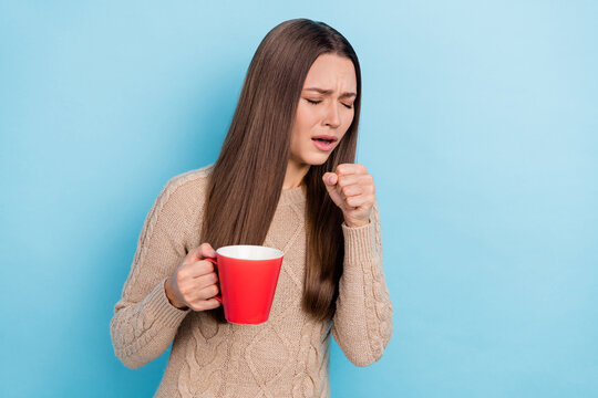 Portrait of attractive unhealthy girl drinking herbal tea coughing isolated over bright blue color background