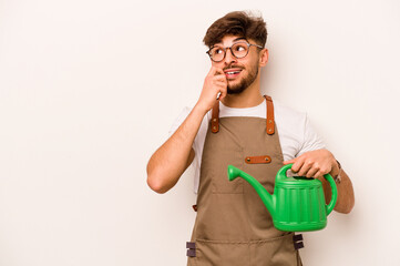 Young gardener hispanic man holding a watering can isolated on white background relaxed thinking about something looking at a copy space.