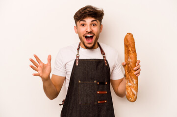 Young baker hispanic man isolated on white background receiving a pleasant surprise, excited and raising hands. - obrazy, fototapety, plakaty