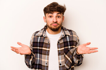 Young hispanic man isolated on white background doubting and shrugging shoulders in questioning...