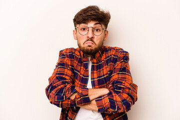 Young hispanic man isolated on white background shrugs shoulders and open eyes confused.