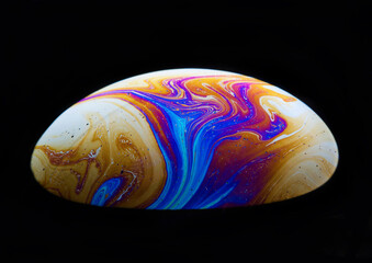 Close-up shot of a rainbow soap bubble in a dark background.