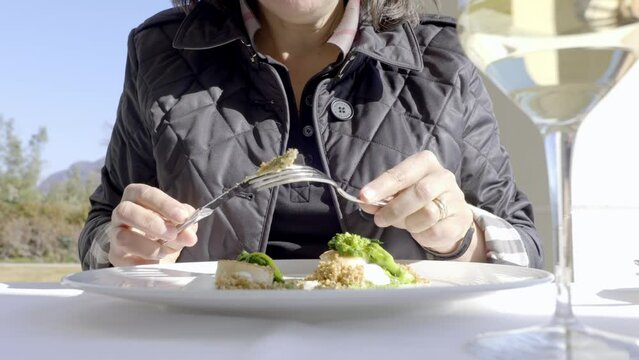 Woman Eating in a Luxury Restaurant Seared scallops with Turnip Greens and Buffalo Stracciatella Cheese and Aromatic Bread in a Sunny Day in Switzerland.
