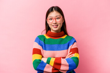 Young Chinese woman isolated on pink background who feels confident, crossing arms with determination.