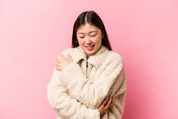 Young Chinese woman isolated on pink background laughing and having fun.