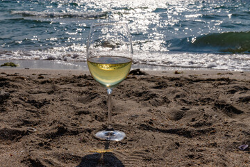 Romantic glass of white wine, on the sea beach. Wine tasting and relaxation at the resort