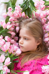  Portrait of a cute little girl with flowers in a pink dress. Girl lady in flowers. Mother's Day, top view. Spring portrait.
