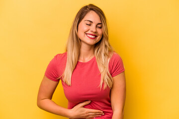 Obraz premium Young caucasian woman isolated on yellow background touches tummy, smiles gently, eating and satisfaction concept.