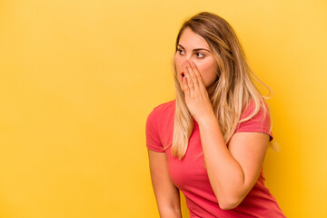 Young caucasian woman isolated on yellow background being shocked because of something she has seen.