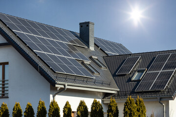Solar panels on the roof of the house with a blue sky on the background © Adam Nowak/Wirestock Creators