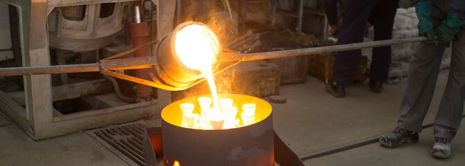 Workers molding product in the foundry from melted metal. Pouring melted metal