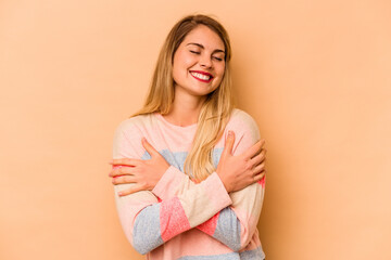 Young caucasian woman isolated on beige background laughing and having fun.