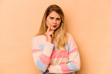 Young caucasian woman isolated on beige background contemplating, planning a strategy, thinking about the way of a business.