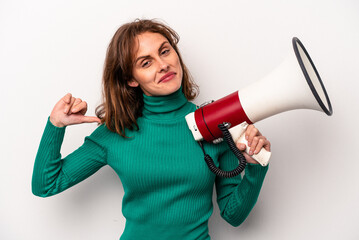 Young caucasian woman holding a megaphone isolated on white background feels proud and self confident, example to follow.