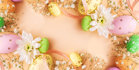 Easter background with eggs and flowers. Top view on a flat orange background. Greeting card template with a space to copy.