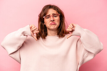 Young caucasian woman isolated on pink background showing a dislike gesture, thumbs down....